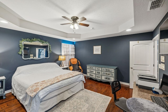 bedroom featuring dark hardwood / wood-style floors, ceiling fan, a tray ceiling, and a textured ceiling