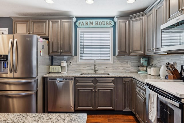 kitchen with stainless steel appliances, light stone countertops, sink, and backsplash