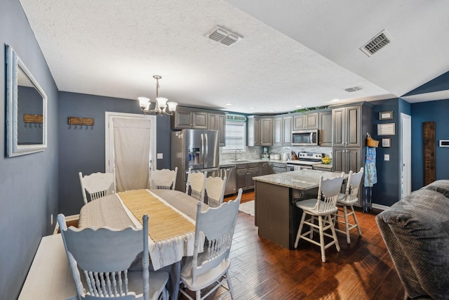 dining area featuring an inviting chandelier, dark hardwood / wood-style floors, sink, and a textured ceiling