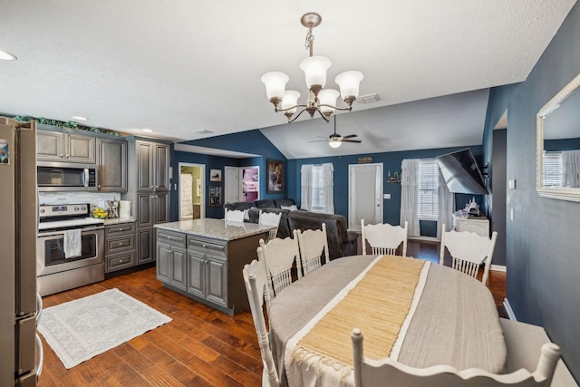 dining area featuring an inviting chandelier, lofted ceiling, dark wood-type flooring, and a textured ceiling