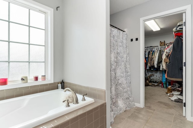 bathroom with tile patterned flooring, tiled tub, and a wealth of natural light