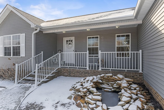 snow covered property entrance featuring a porch