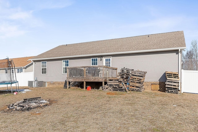 back of house featuring central AC unit, a yard, a deck, and a trampoline