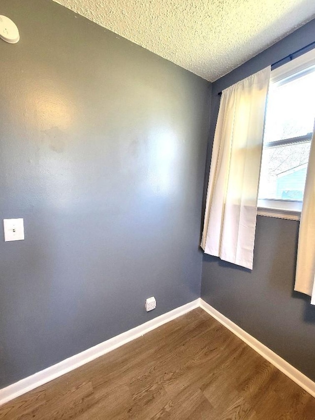 spare room featuring wood-type flooring and a textured ceiling