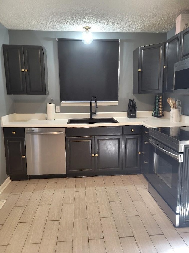 kitchen featuring appliances with stainless steel finishes, sink, and a textured ceiling