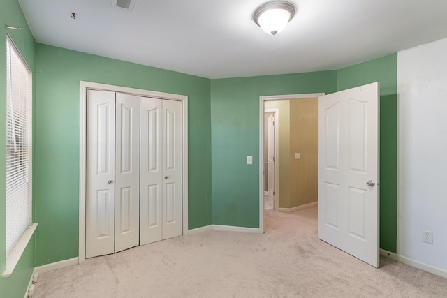 unfurnished bedroom with light colored carpet and a closet