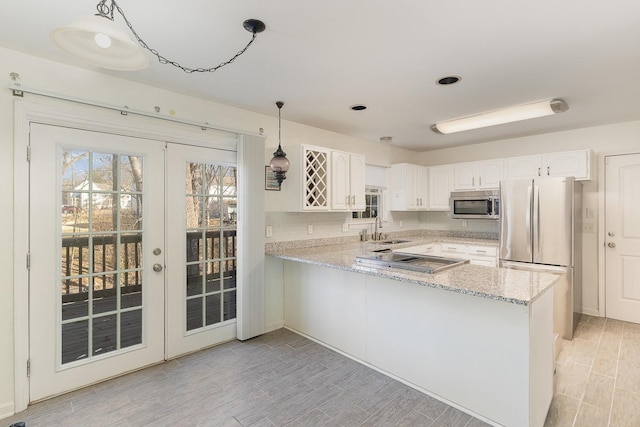 kitchen featuring stainless steel appliances, white cabinetry, pendant lighting, and kitchen peninsula