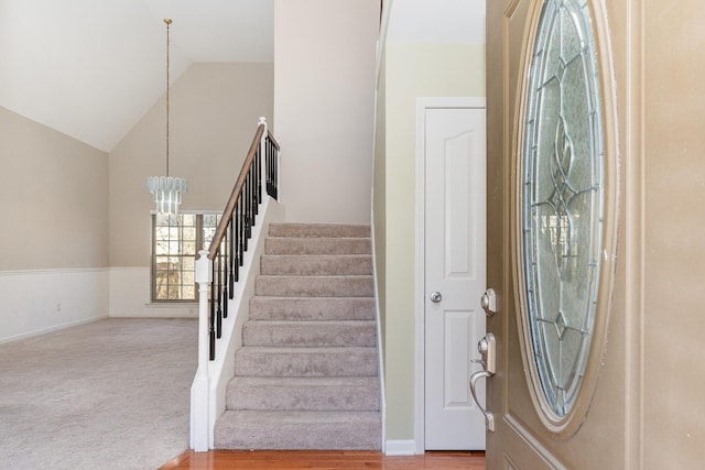 foyer with carpet flooring, vaulted ceiling, and a notable chandelier