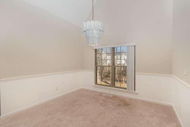 spare room with vaulted ceiling, a chandelier, and carpet flooring