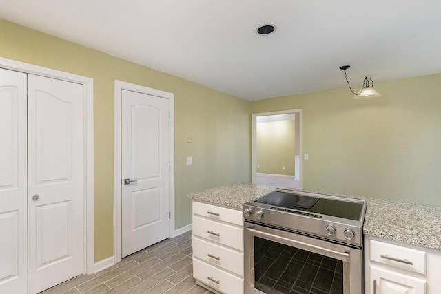 kitchen featuring high end range, light stone counters, and white cabinetry