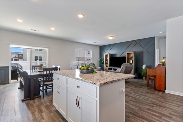 kitchen featuring white cabinetry, dark hardwood / wood-style flooring, light stone counters, and a kitchen island