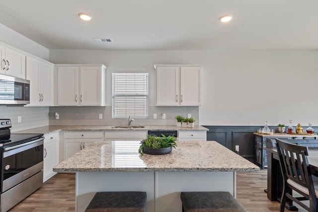 kitchen featuring appliances with stainless steel finishes, sink, a kitchen island, and white cabinets