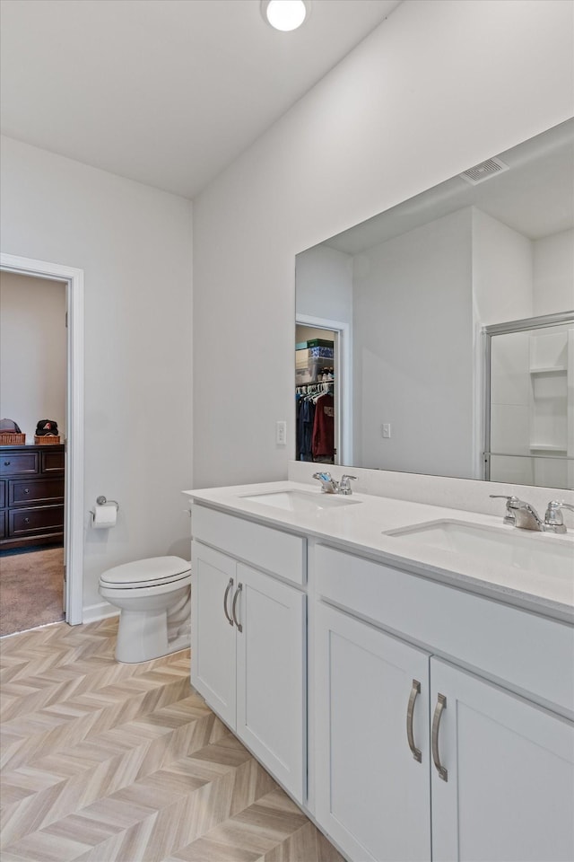 bathroom with an enclosed shower, vanity, parquet floors, and toilet