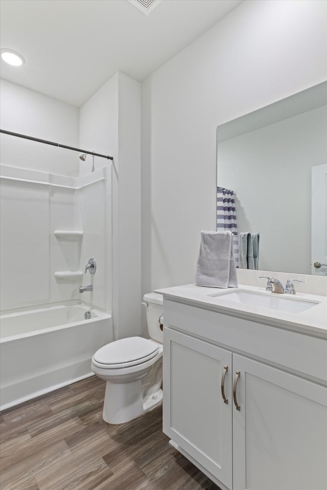 full bathroom with hardwood / wood-style flooring, vanity, shower / tub combo, and toilet