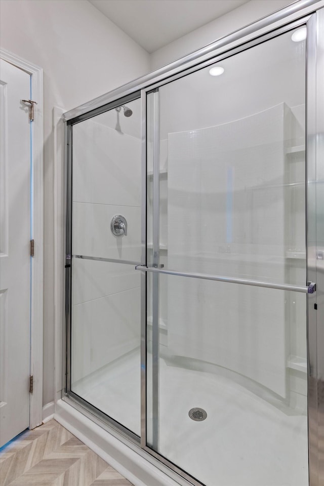 bathroom with a shower with door and parquet flooring