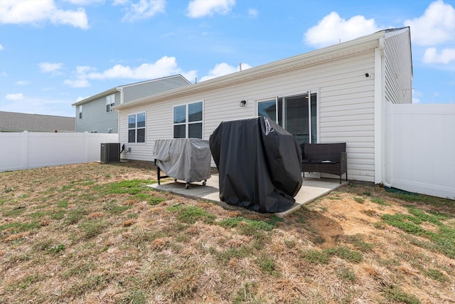 rear view of property with a lawn, central AC unit, and a patio area