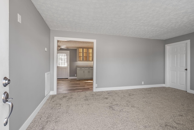 carpeted empty room with a textured ceiling