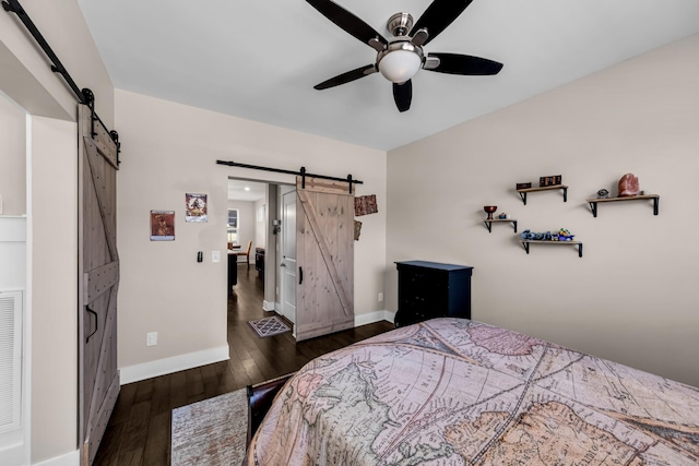 bedroom featuring ceiling fan, a barn door, and dark hardwood / wood-style flooring