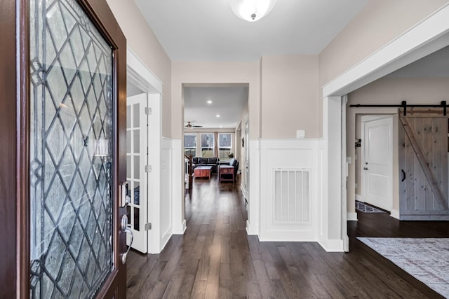 foyer featuring dark wood-type flooring, a barn door, and ceiling fan