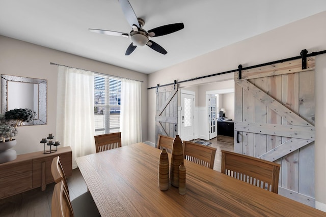 dining space featuring wood-type flooring, a barn door, and ceiling fan