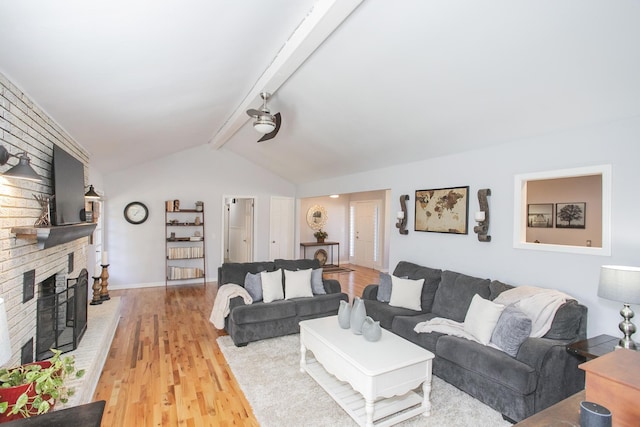 living room with vaulted ceiling with beams, a fireplace, and light wood-type flooring