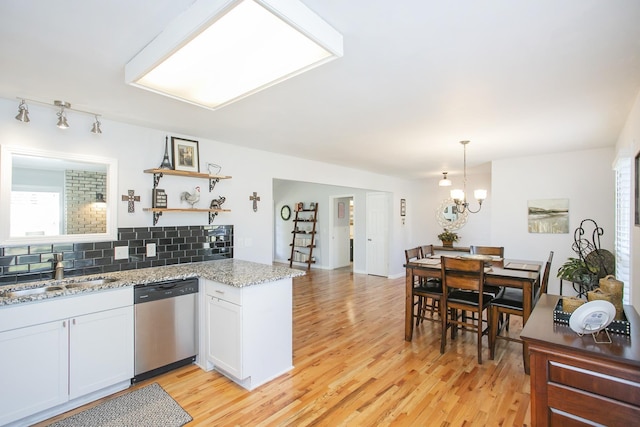 kitchen featuring sink, dishwasher, white cabinetry, decorative backsplash, and kitchen peninsula