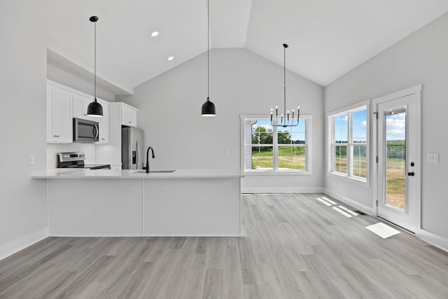 kitchen with light wood finished floors, white cabinets, stainless steel appliances, light countertops, and a sink