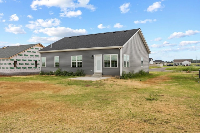 back of house with entry steps, a patio area, and a lawn