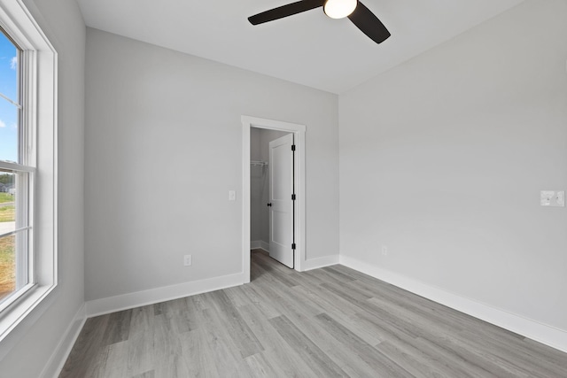 spare room with ceiling fan, light wood-type flooring, and baseboards