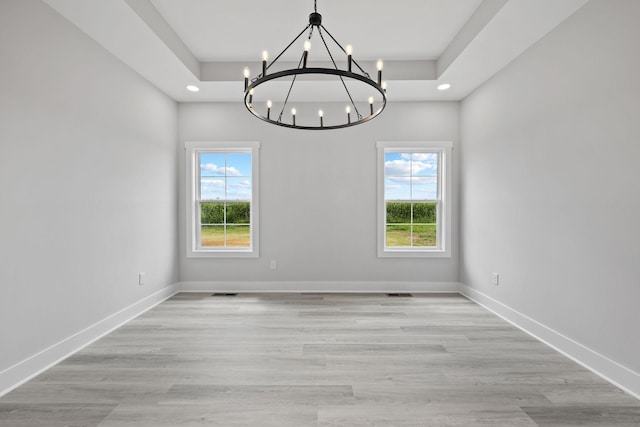 unfurnished room featuring baseboards, a raised ceiling, and wood finished floors