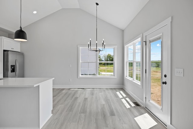 unfurnished dining area featuring visible vents, a chandelier, baseboards, light wood-style flooring, and high vaulted ceiling