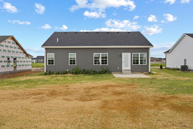 back of house with entry steps, roof with shingles, a lawn, and central air condition unit