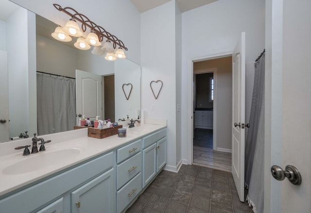 full bath with a sink, baseboards, and double vanity