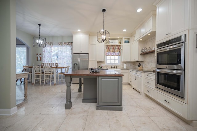 kitchen featuring tasteful backsplash, a center island, appliances with stainless steel finishes, white cabinetry, and open shelves