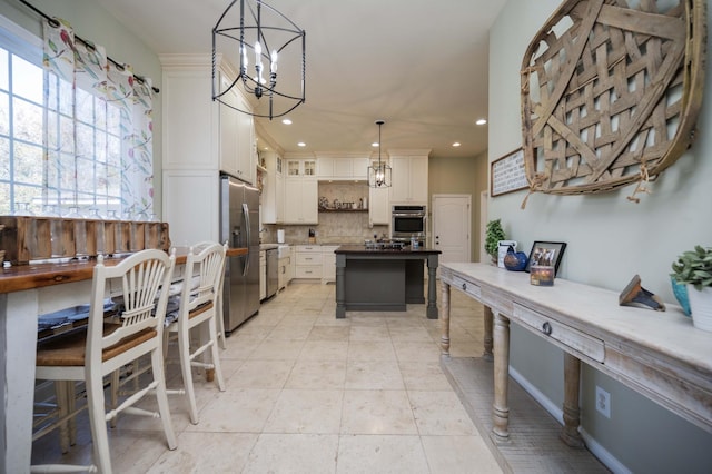 kitchen featuring a notable chandelier, decorative backsplash, stainless steel appliances, white cabinets, and glass insert cabinets