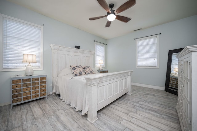 bedroom with a ceiling fan, wood finished floors, visible vents, and baseboards