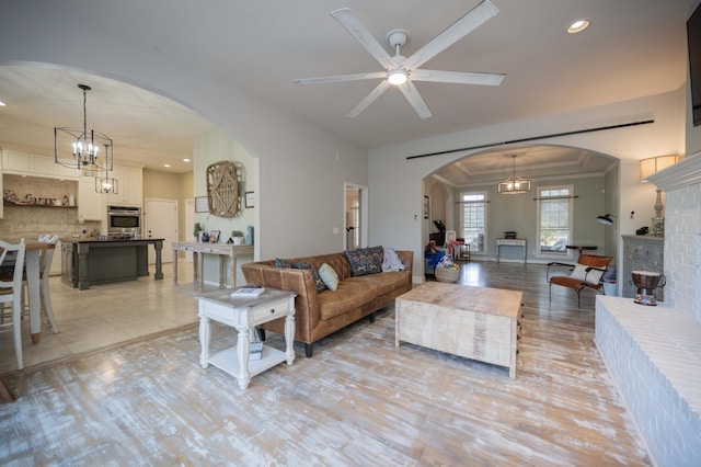 living area featuring recessed lighting, a fireplace, arched walkways, light wood-style floors, and crown molding