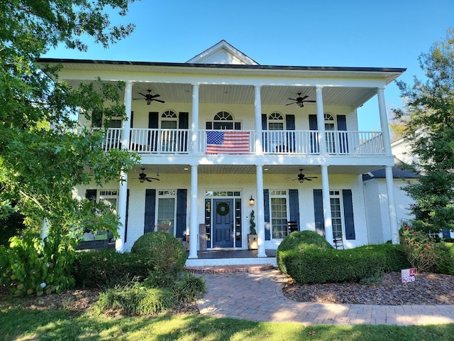 neoclassical / greek revival house with a porch, a balcony, a ceiling fan, and brick siding