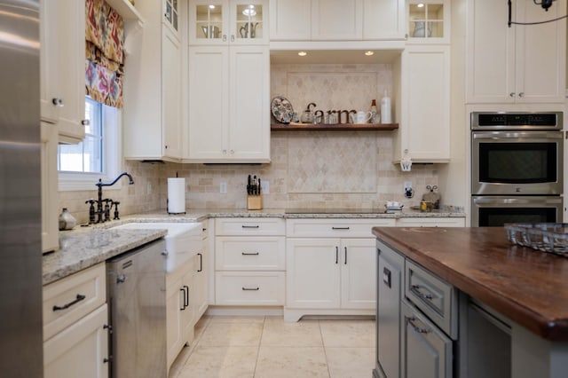 kitchen featuring a sink, wood counters, tasteful backsplash, and appliances with stainless steel finishes