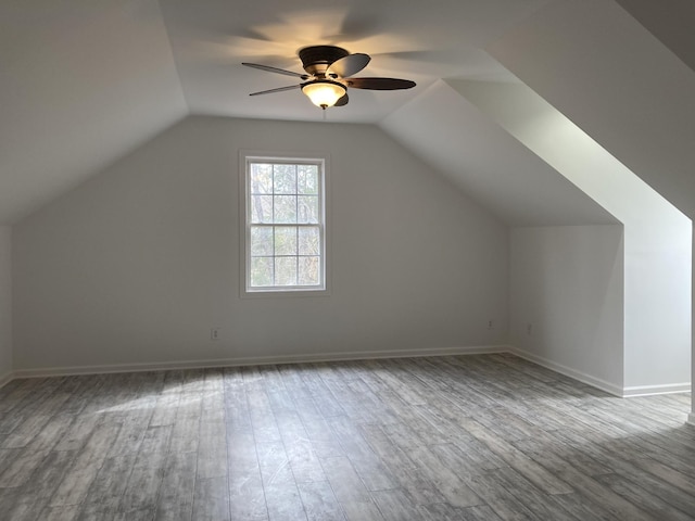 additional living space with vaulted ceiling, wood finished floors, and baseboards