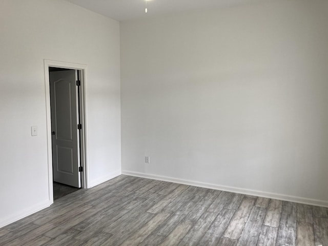 empty room with dark wood-type flooring and baseboards