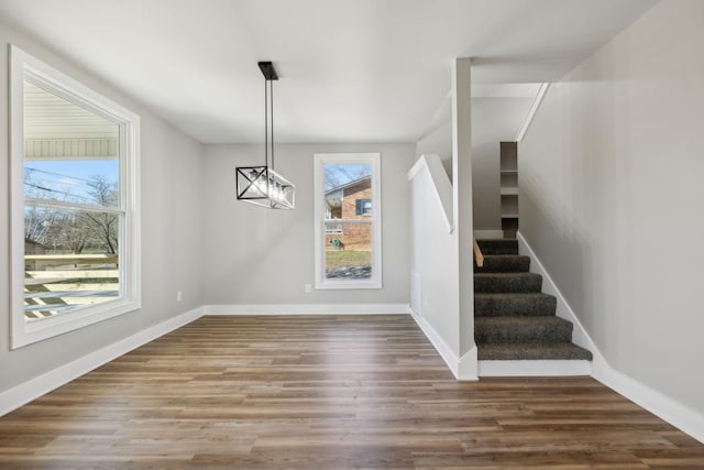 unfurnished dining area featuring plenty of natural light, dark wood-type flooring, and a notable chandelier