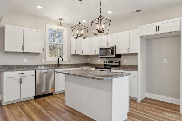 kitchen featuring sink, hanging light fixtures, a kitchen island, stainless steel appliances, and white cabinets