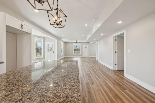 unfurnished living room with a notable chandelier and light hardwood / wood-style floors