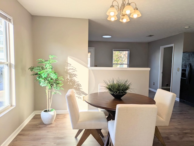 dining space featuring wood-type flooring and a notable chandelier