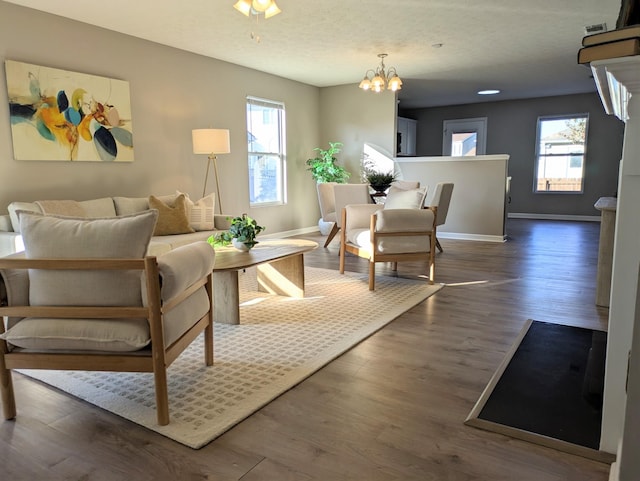 living area featuring a healthy amount of sunlight, dark hardwood / wood-style floors, and a chandelier