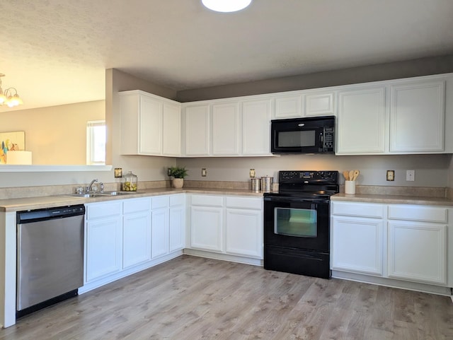 kitchen with sink, white cabinets, a notable chandelier, black appliances, and light hardwood / wood-style flooring