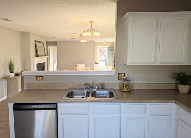 kitchen with pendant lighting, white cabinetry, sink, stainless steel dishwasher, and an inviting chandelier