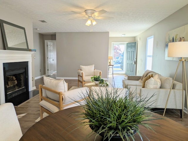 living room featuring ceiling fan, wood-type flooring, and a textured ceiling