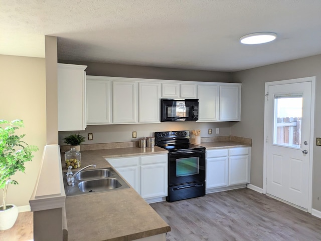 kitchen featuring sink, white cabinetry, black appliances, light hardwood / wood-style floors, and a textured ceiling